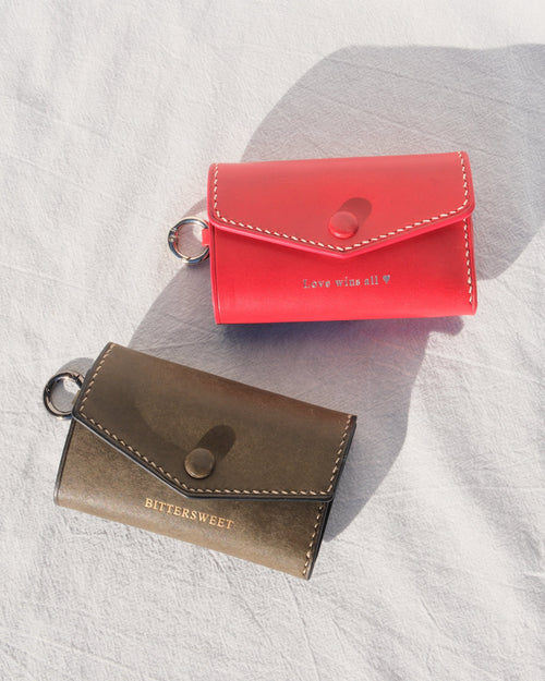 Two small leather wallets, one red and one olive.