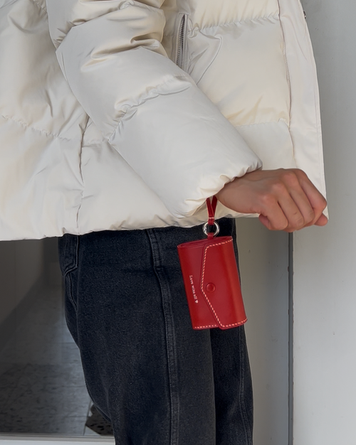 Person wearing a light-colored puffer jacket holding a red bag.